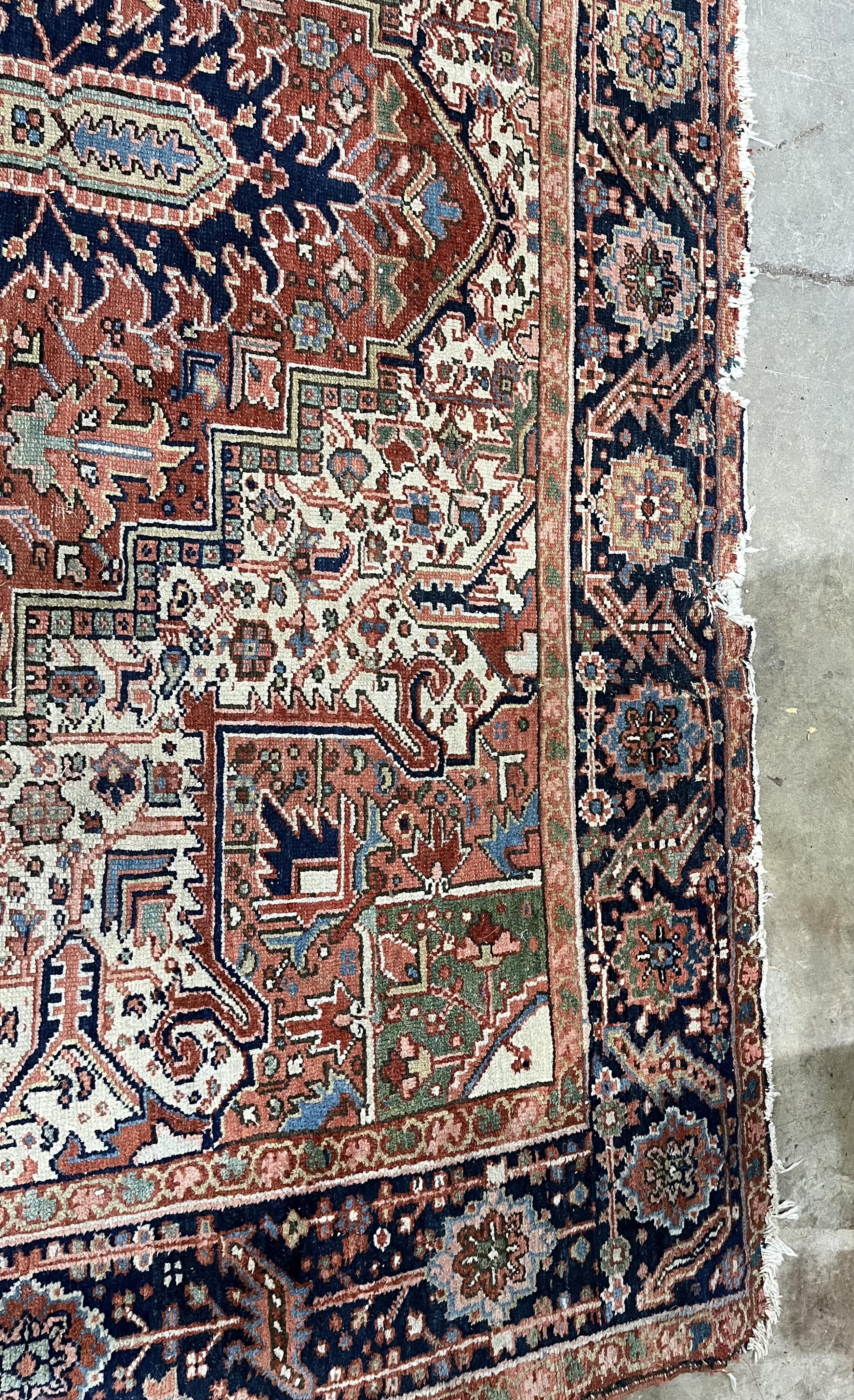 An antique Heriz brick red ground carpet, 350 x 274cm. Condition - fair